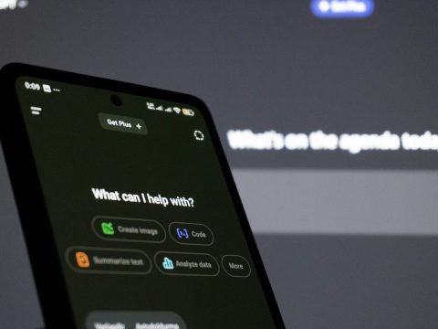 Smartphone showing the ChatGPT app in front of a screen