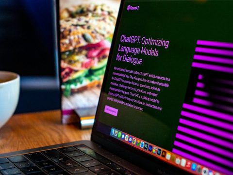 Laptop showing a ChatGPT article next to a sandwich poster